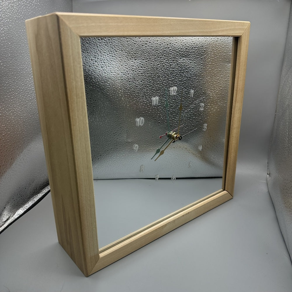 Wooden-framed clock with a reflective face on a gray background