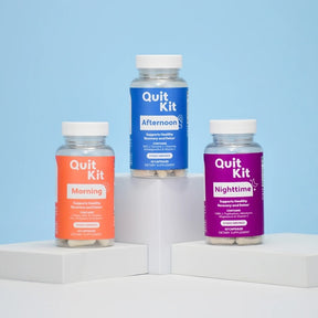 Three bottles of Quit Kit supplements on a white platform with a blue background
